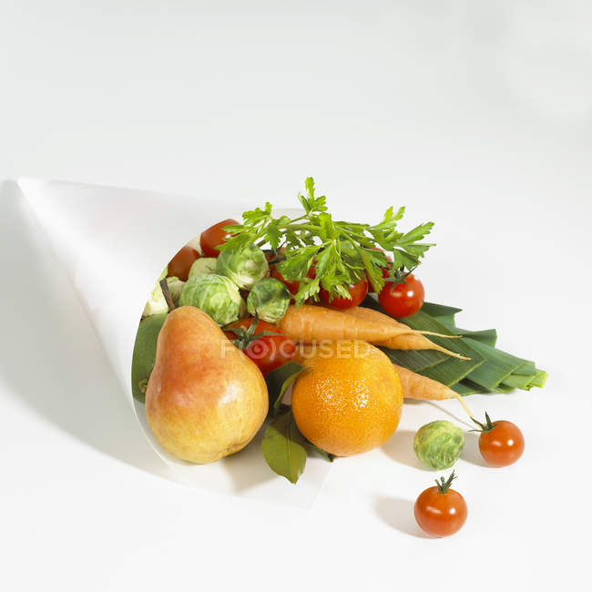 Varios tipos de frutas y verduras en bolsa de papel sobre superficie blanca - foto de stock