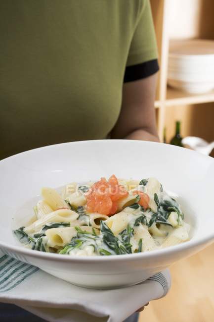 Woman holding plate of penne pasta — Stock Photo