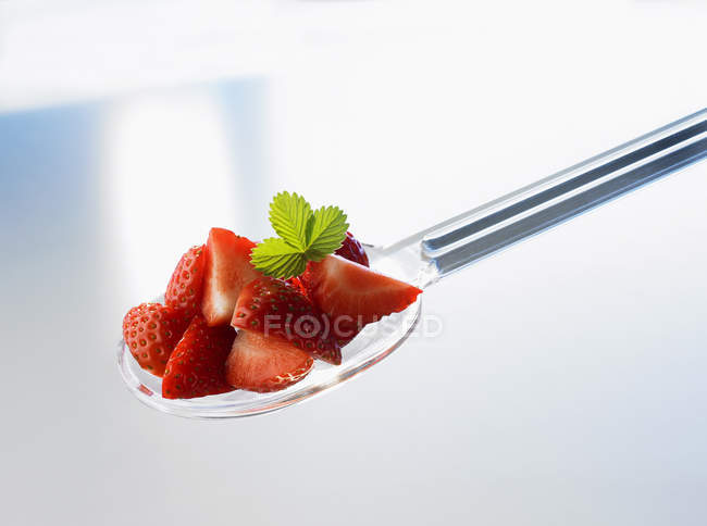 Varias piezas de fresa en una cuchara de plástico - foto de stock