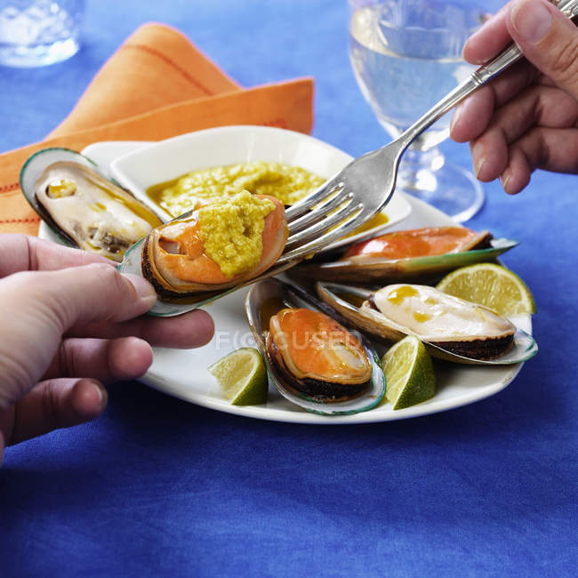 Man eating mussels with sauce — Stock Photo