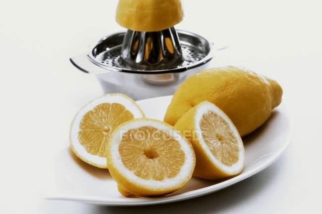 Limones y exprimidor fresco a la mitad - foto de stock