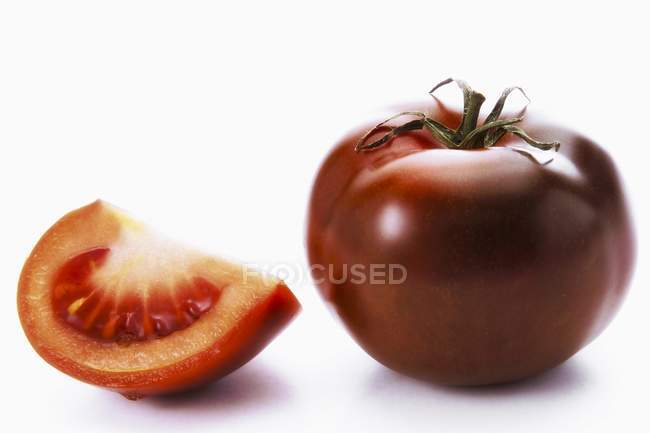 Whole tomato and wedge — Stock Photo