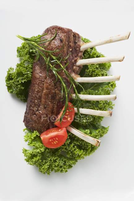 Roasted rack of lamb garnished with tomatoes — Stock Photo