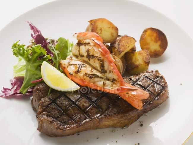 Prawn and beef steak with roasted potatoes — Stock Photo