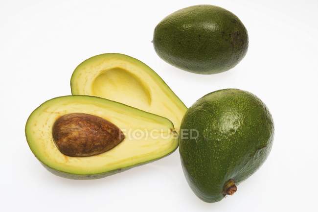 Three avocados whole and halved — Stock Photo