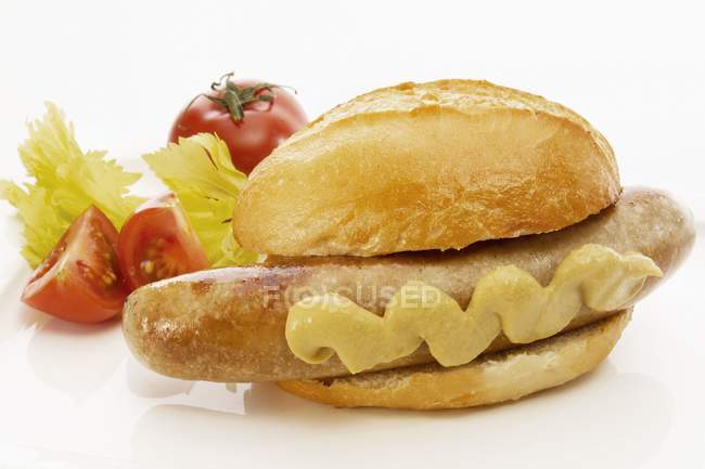 Sausage with mustard in bread roll — Stock Photo