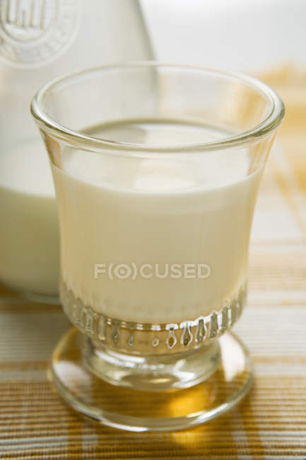 Verre de lait devant la carafe de lait — Photo de stock