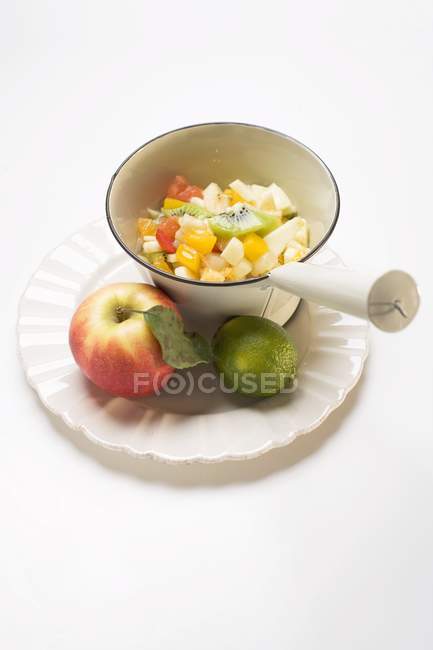 Vista de cerca de ensalada de frutas con manzana y lima en el plato - foto de stock