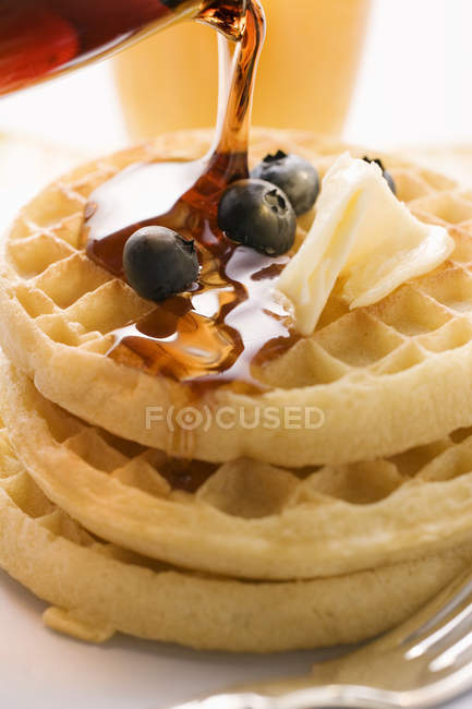 Pouring maple syrup over waffles — Stock Photo