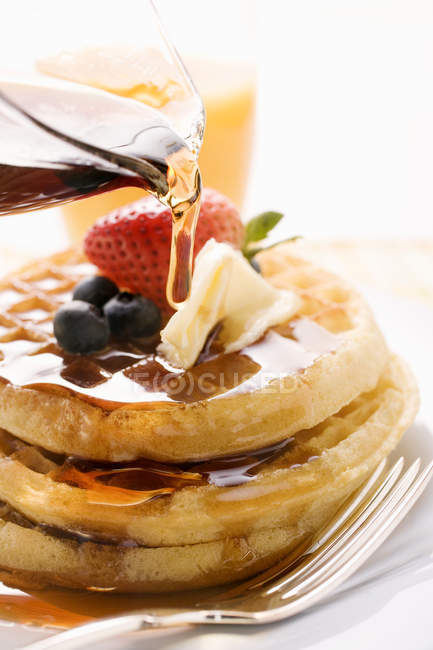 Despejar xarope de bordo sobre waffles — Fotografia de Stock