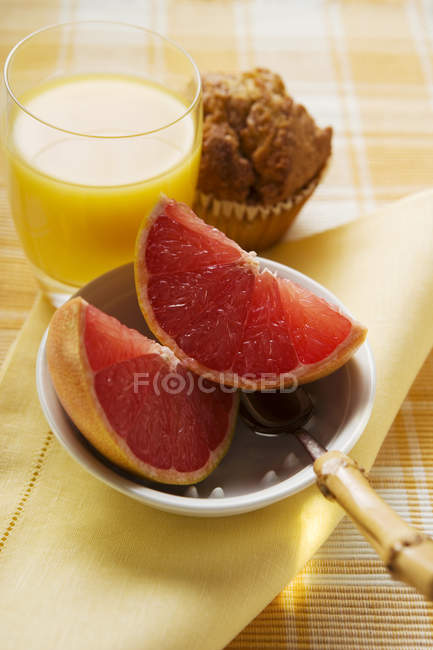 Grapefruit slices in a bowl with muffin — Stock Photo