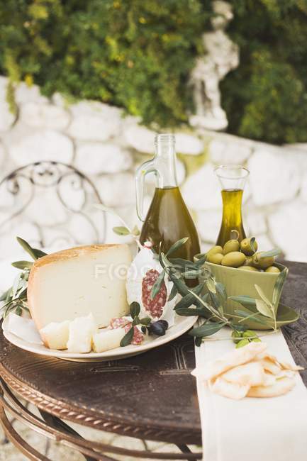 Cheese with salami and olives on table — Stock Photo