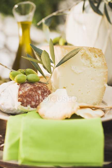 Cheese with salami and olives on table — Stock Photo