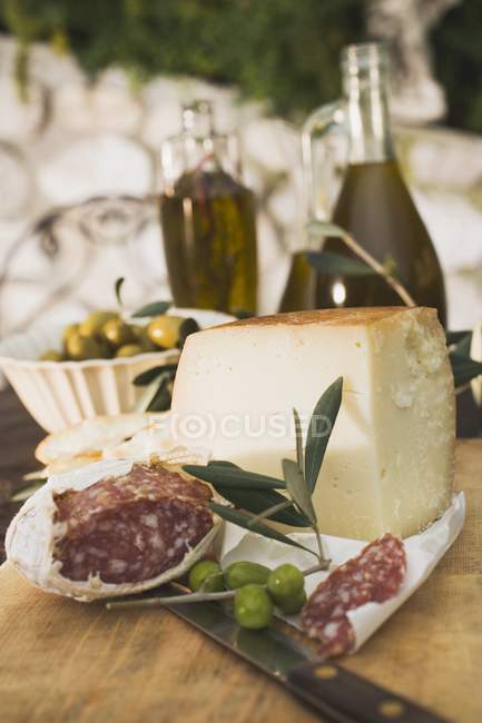 Сыр с салями и оливками на столе — стоковое фото
