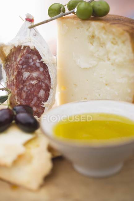 Salame con olive e parmigiano su superficie di legno — Foto stock