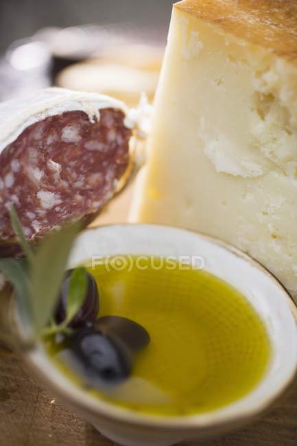 Salami with olives and Parmesan on wooden surface — Stock Photo
