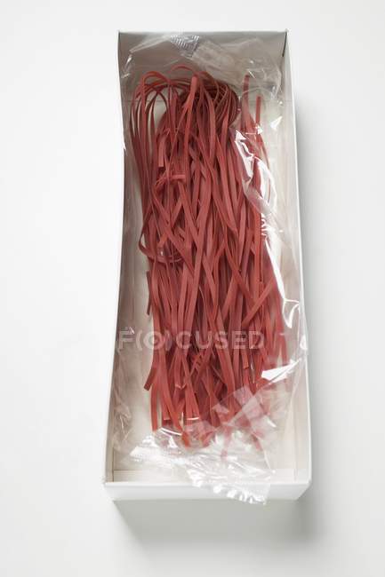 Red raw tagliatelle pasta in packaging — Stock Photo