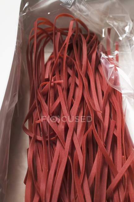 Red raw tagliatelle pasta in packaging — Stock Photo