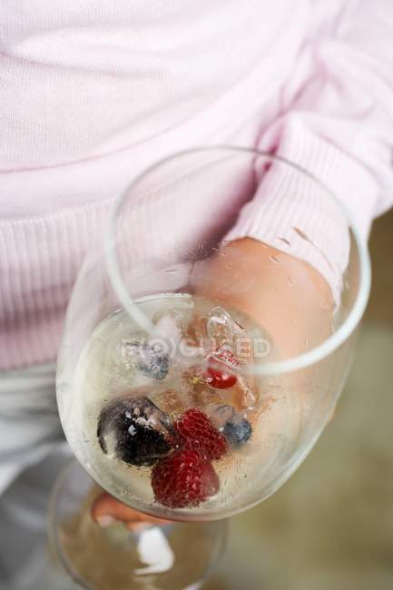 Glass of champagne with berry ice cubes — Stock Photo