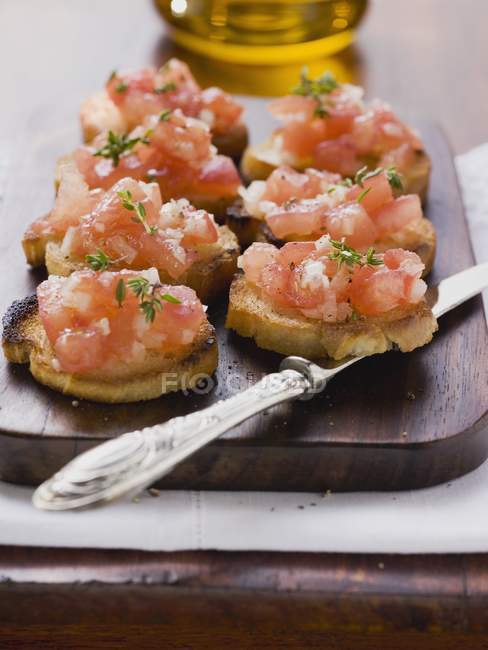 Bruschetta toasted bread with tomatoes and garlic over woden desk with knife — Stock Photo