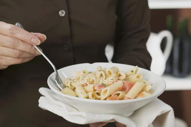 Female chef holding plate of penne — Stock Photo
