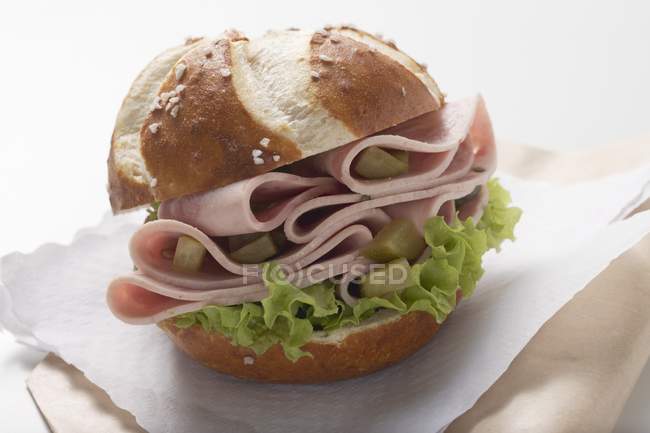 Pretzel roll with sausages and gherkins — Stock Photo