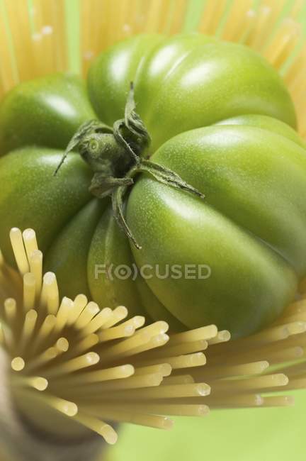 Green tomato in spaghetti — Stock Photo