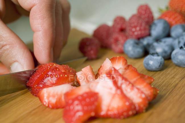 Mains humaines coupant des fraises — Photo de stock
