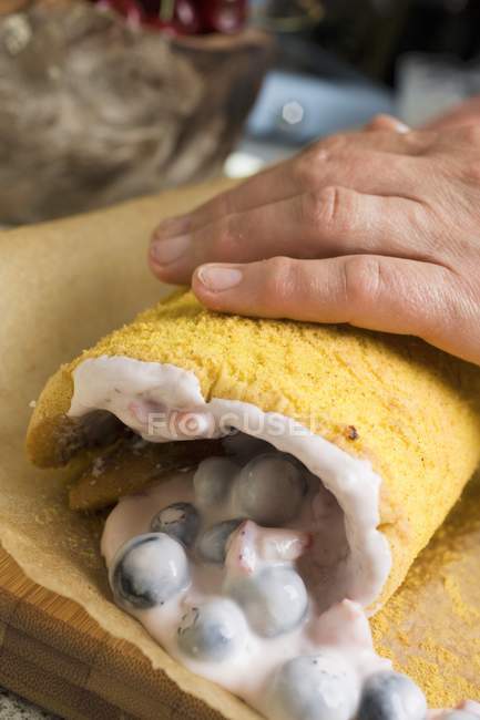 Closeup cropped view of hand rolling a sponge roulade — Stock Photo