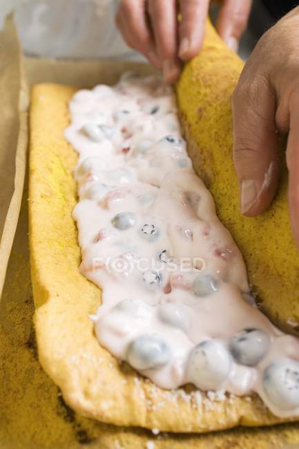 Closeup cropped view of hands rolling sponge roulade — Stock Photo