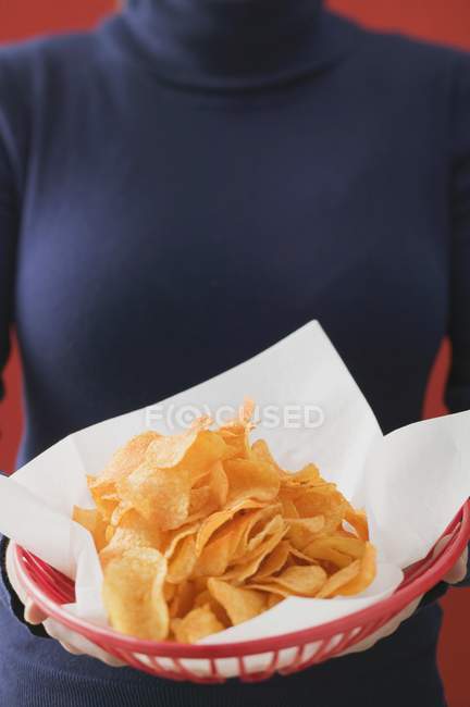 Woman holding basket of crisps — Stock Photo
