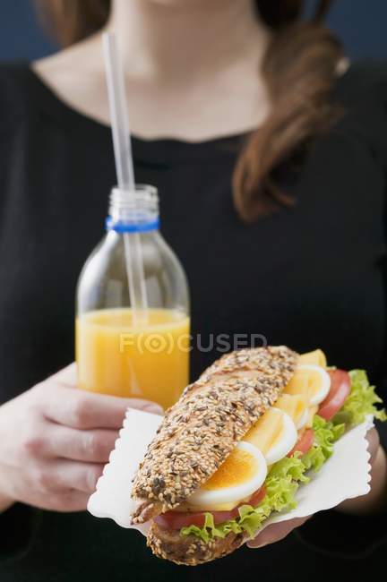 Woman holding sandwich and juice — Stock Photo