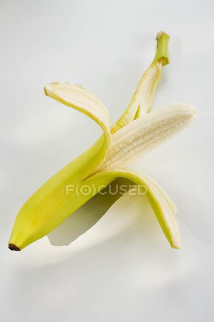 Banana gialla mezza sbucciata — Foto stock