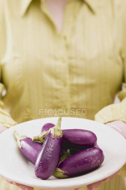 Frau hält Teller mit Auberginen — Stockfoto