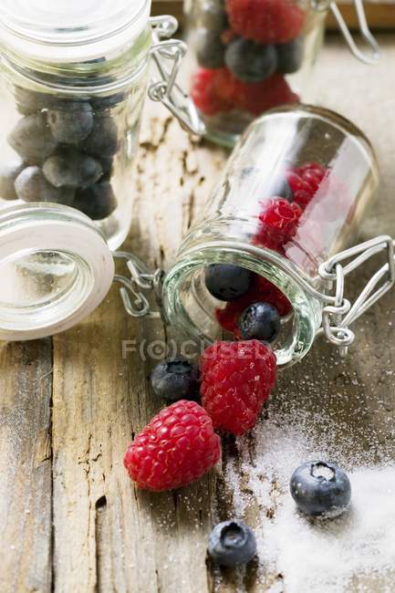 Raspberries and blueberries in preserving jars — Stock Photo