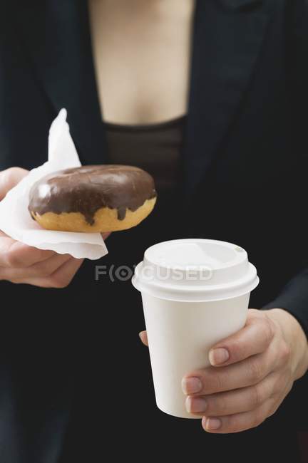 Жінка тримає пончик і чашку кави — стокове фото