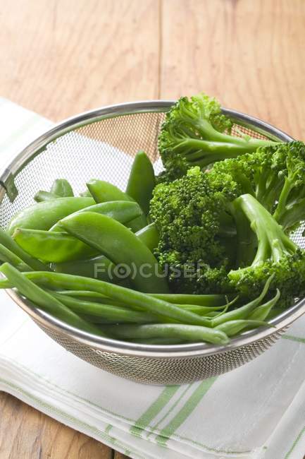 Mangetout and broccoli in sieve — Stock Photo
