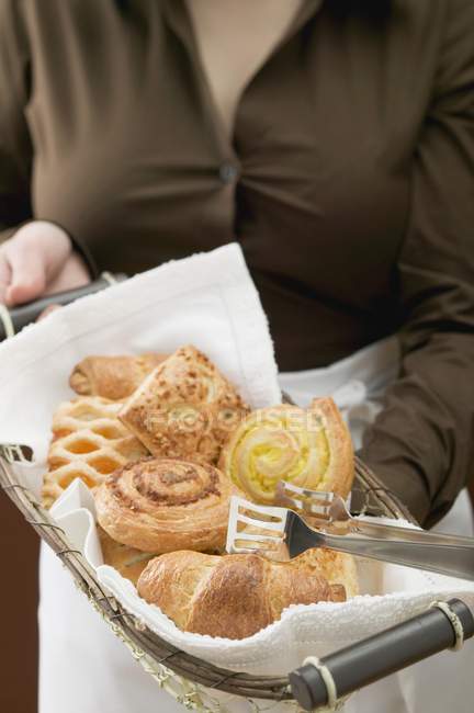 Cropped view of woman holding basket of sweet pastries — Stock Photo