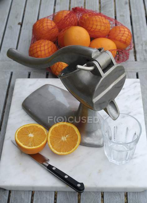 Prensa de zumo y naranjas frescas - foto de stock