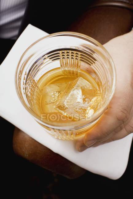 Hand holding glass of whisky — Stock Photo
