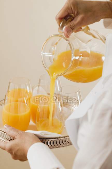 Выливание апельсинового сока в стекло — стоковое фото