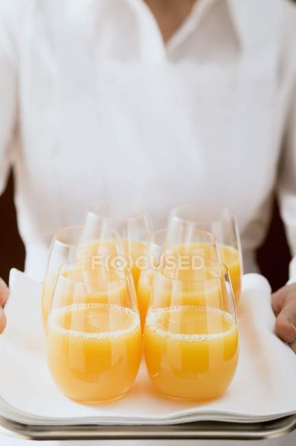 Camarera sirviendo jugo de naranja en vasos - foto de stock