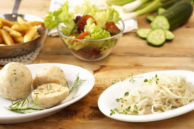 A selection of accompaniments on white plates over wooden surface — Stock Photo