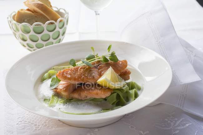 Salmon fillet on green ribbon pasta — Stock Photo