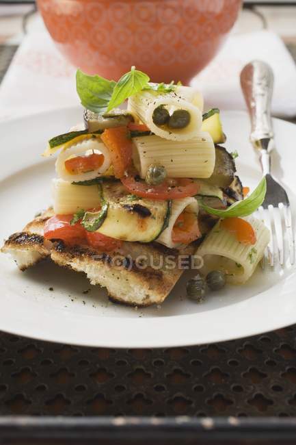 Pasta salad with vegetables on grilled bread — Stock Photo