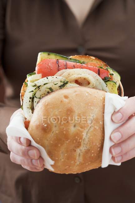 Woman holding toasted roll filled with grilled vegetables in hands — Stock Photo