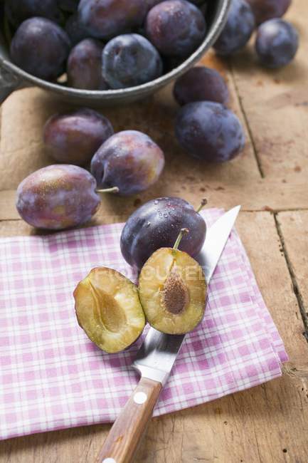 Whole and halved damsons with knife — Stock Photo