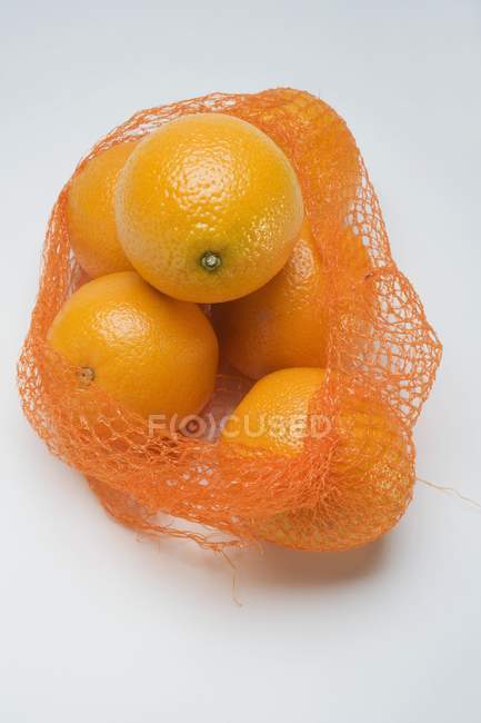 Свіжі стиглі апельсини в сітці — стокове фото
