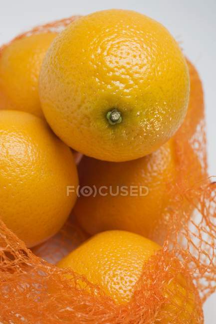 Свежие спелые апельсины в сети — стоковое фото
