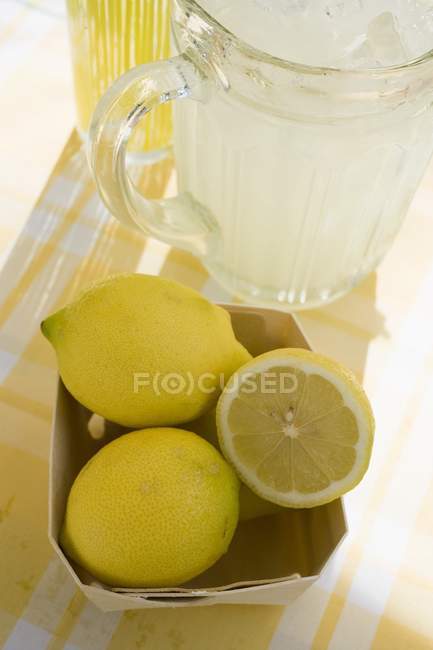 Jug of lemonade and fresh lemons — Stock Photo